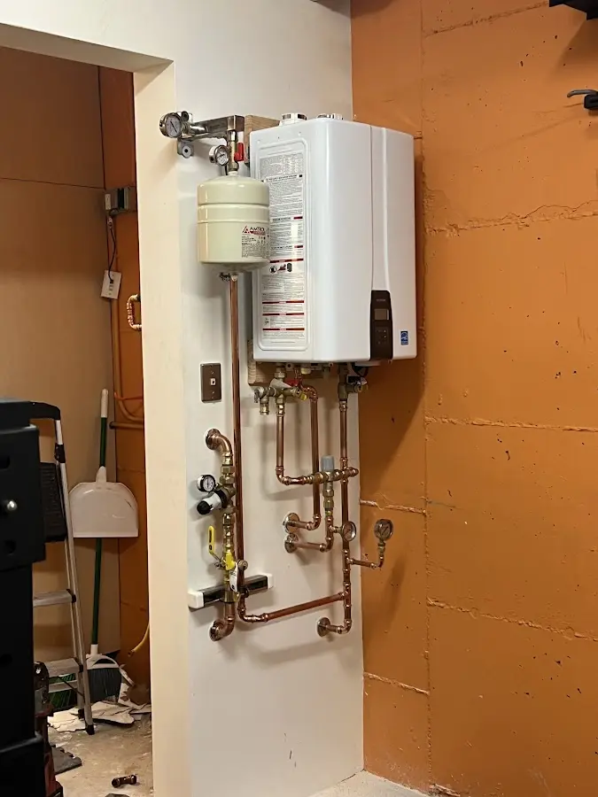 Plumbing technician inspecting water heater connections in Oak Grove